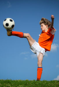 Child kicking playing football.